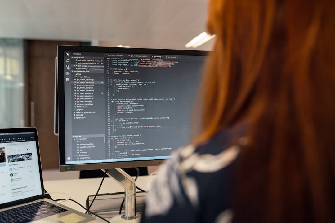 A software developer carefully reviewing code on a monitor in a professional office environment.