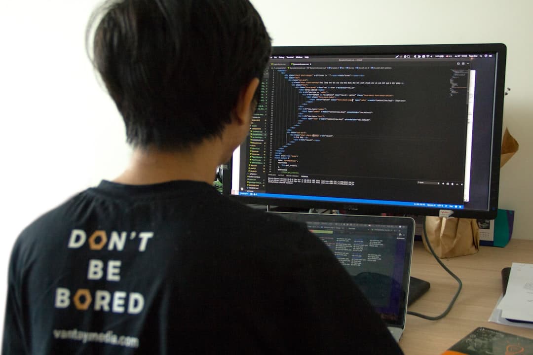 Software developer looking at code on a monitor with a hand on the forehead.