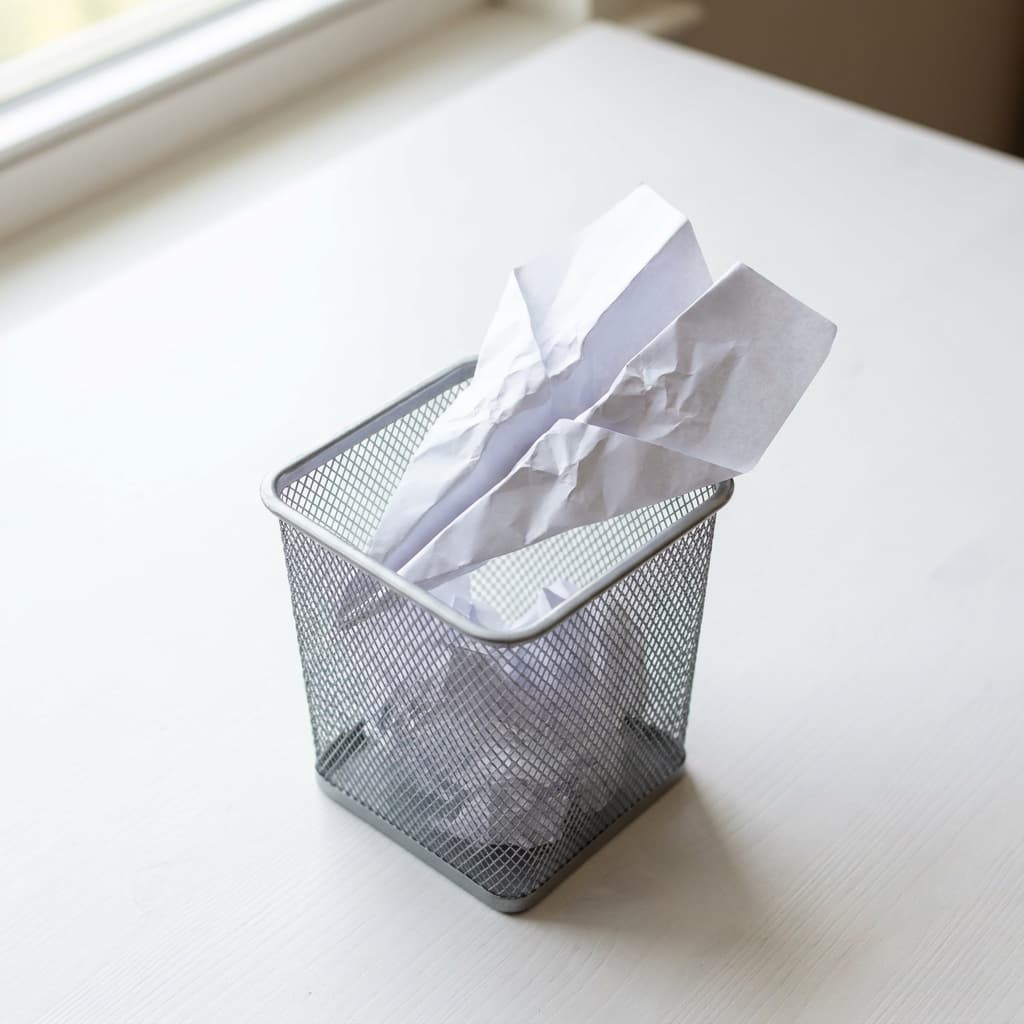 A single crumpled paper airplane resting on a clean white desk, lit by soft natural light, symbolizing a failed attempt or grounded initiative