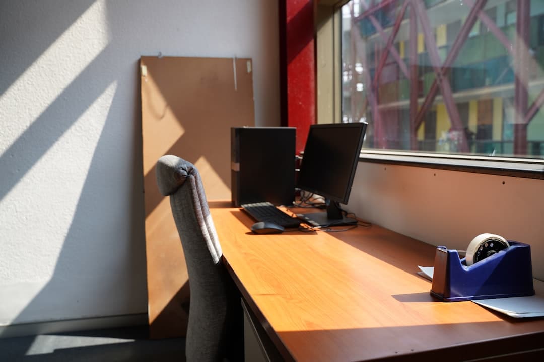 Cardboard box with personal items on an empty office desk in a modern workspace.